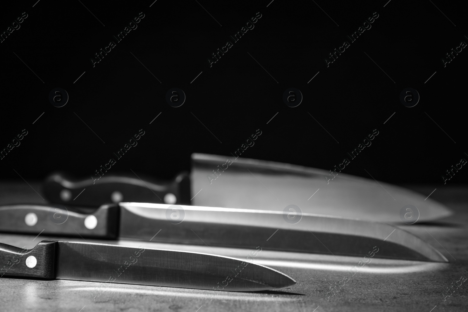 Photo of Sharp knives on table against dark background. Space for text