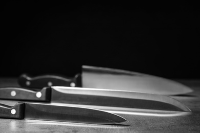 Photo of Sharp knives on table against dark background. Space for text