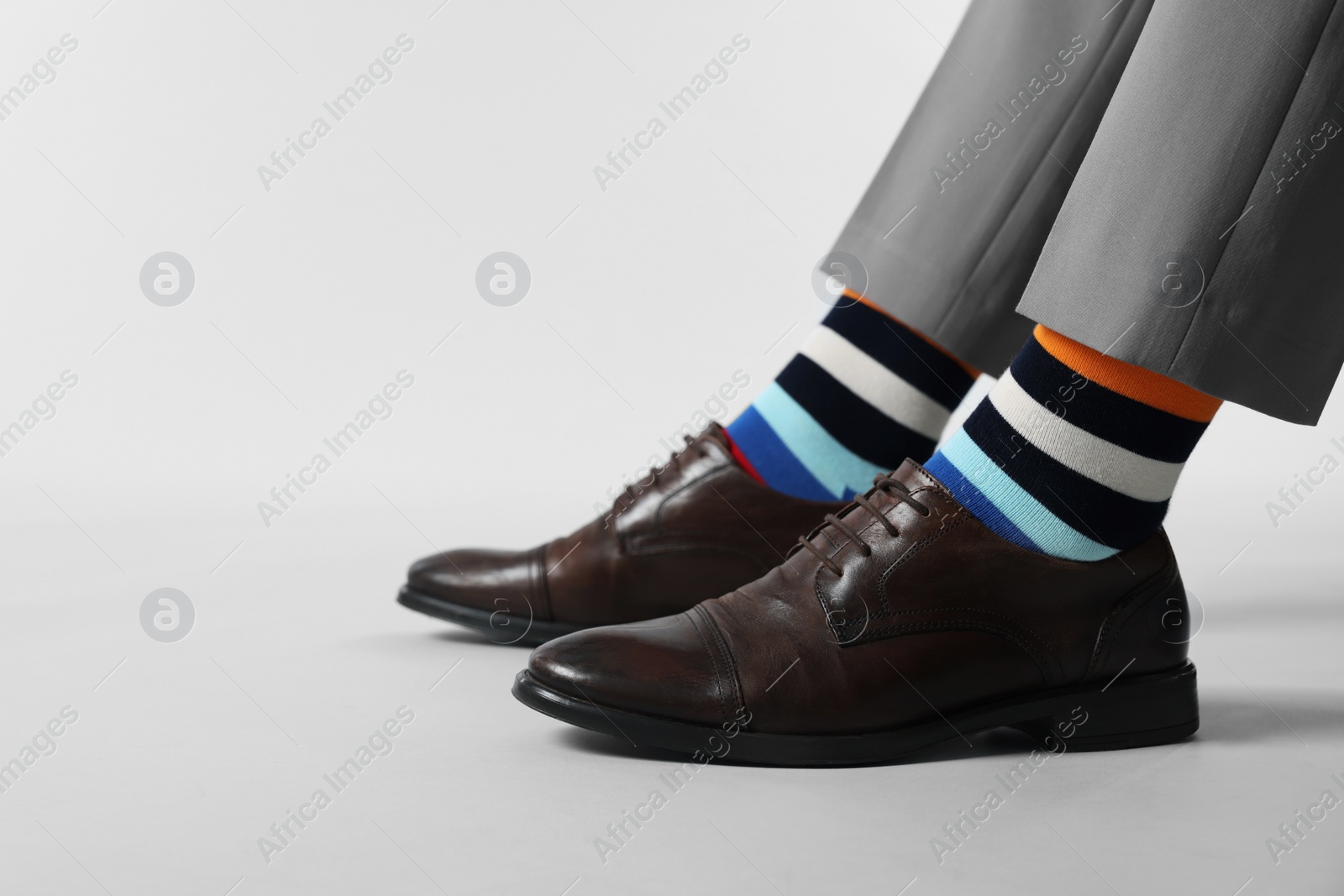 Photo of Man in stylish colorful socks, shoes and pants on white background, closeup. Space for text