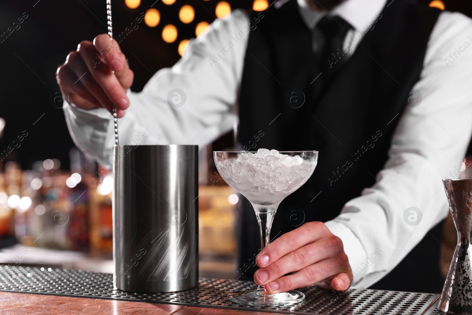 Photo of Bartender with martini glass preparing fresh alcoholic cocktail at bar counter, closeup