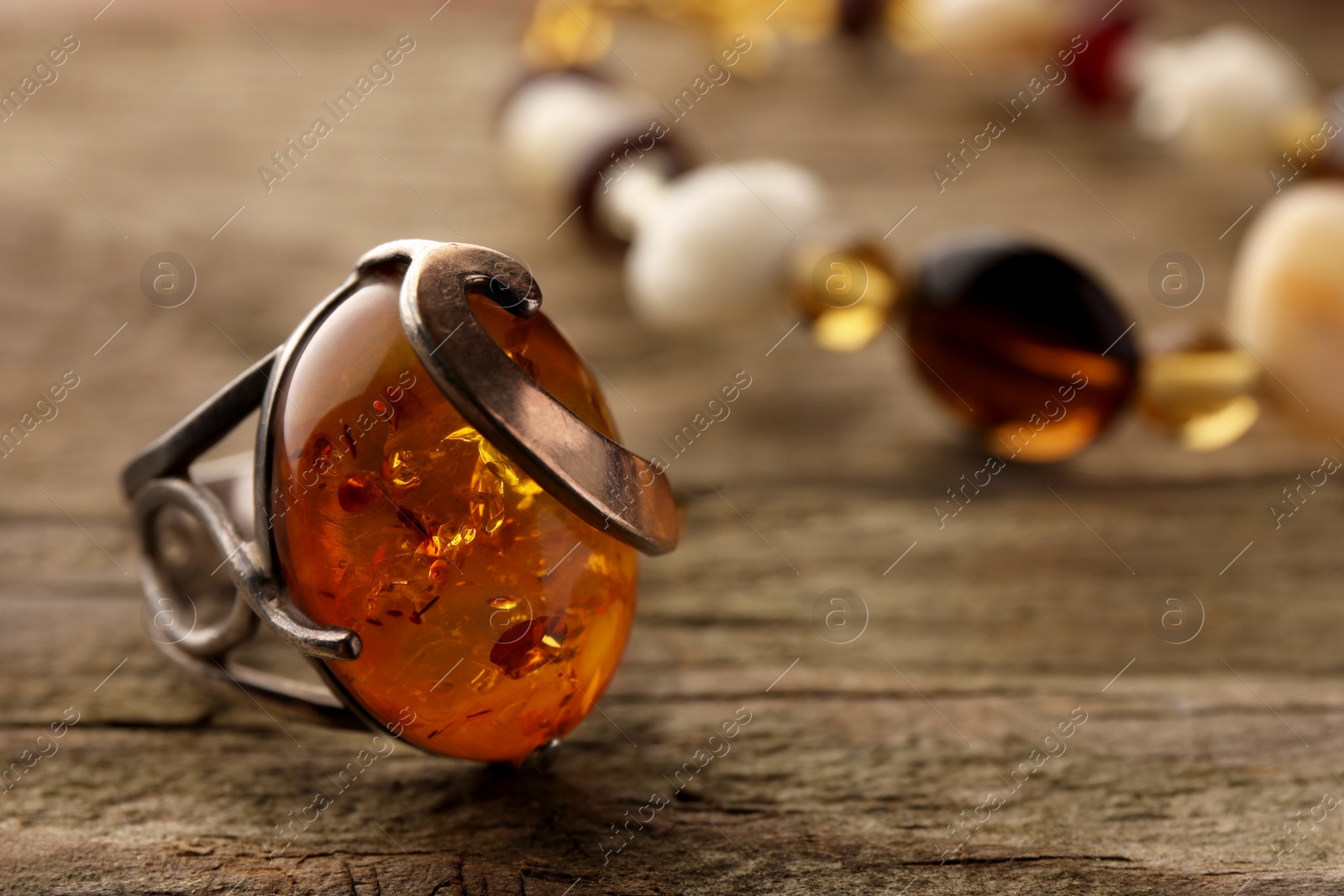 Photo of Beautiful ring with gemstone on wooden surface, closeup. Space for text