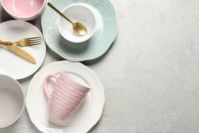 Beautiful ceramic dishware, cup and cutlery on light grey table, flat lay. Space for text