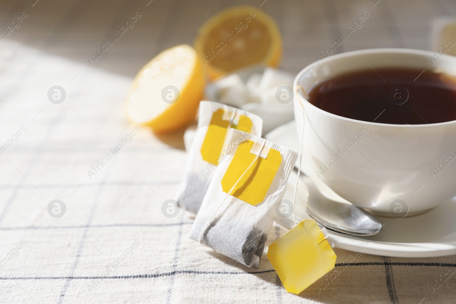 Photo of Tea bags near cup of hot drink on table, closeup. Space for text
