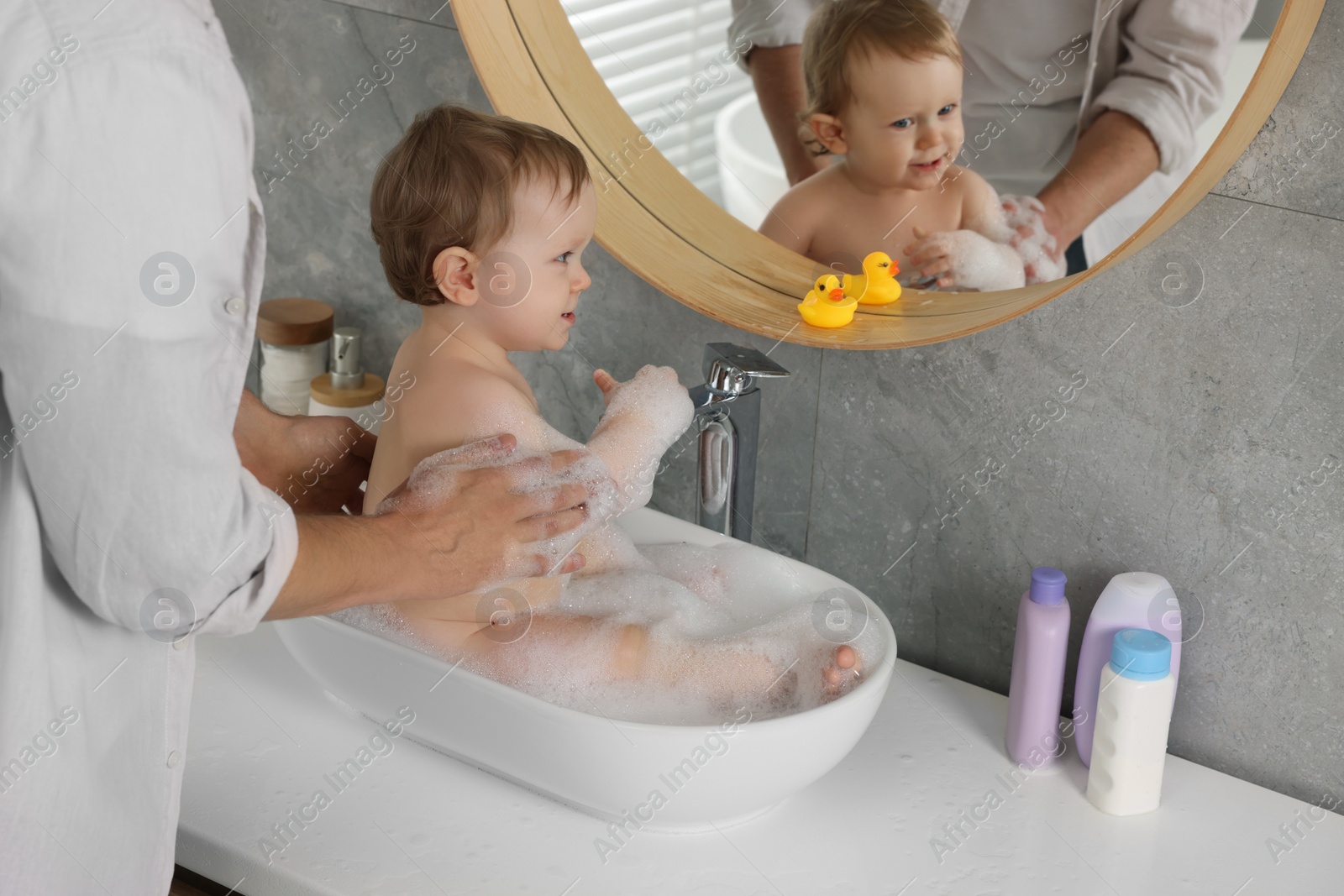 Photo of Father washing his little baby in sink at home