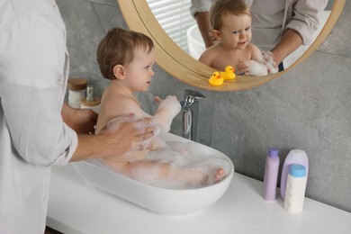 Father washing his little baby in sink at home