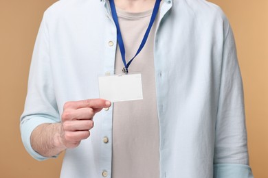 Photo of Man showing empty badge on beige background, closeup