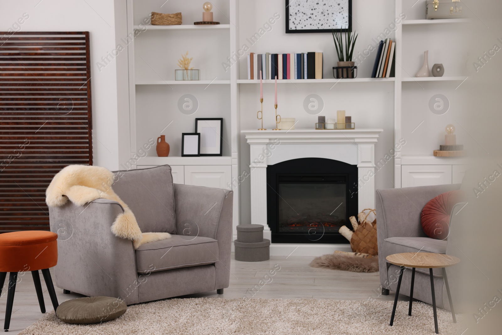 Photo of Comfortable armchairs, fireplace and shelves in living room. Interior design
