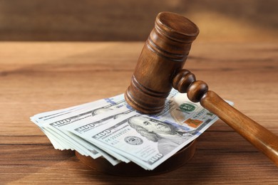 Judge's gavel and money on wooden table, closeup