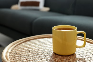 Ceramic mug of tea on wicker table indoors. Mockup for design