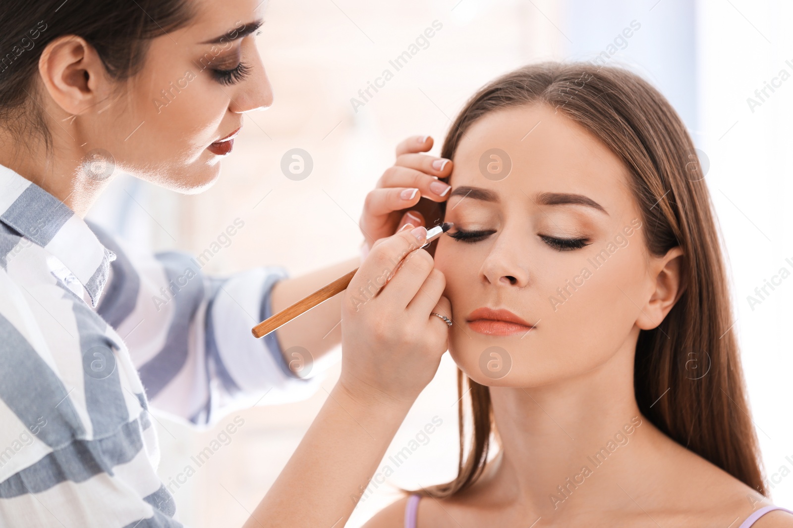 Photo of Professional visage artist applying makeup on woman's face in salon