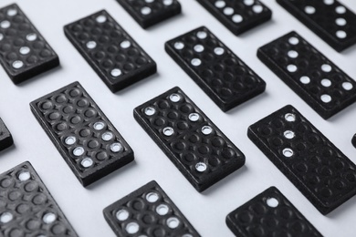 Photo of Set of black domino tiles on white background, closeup