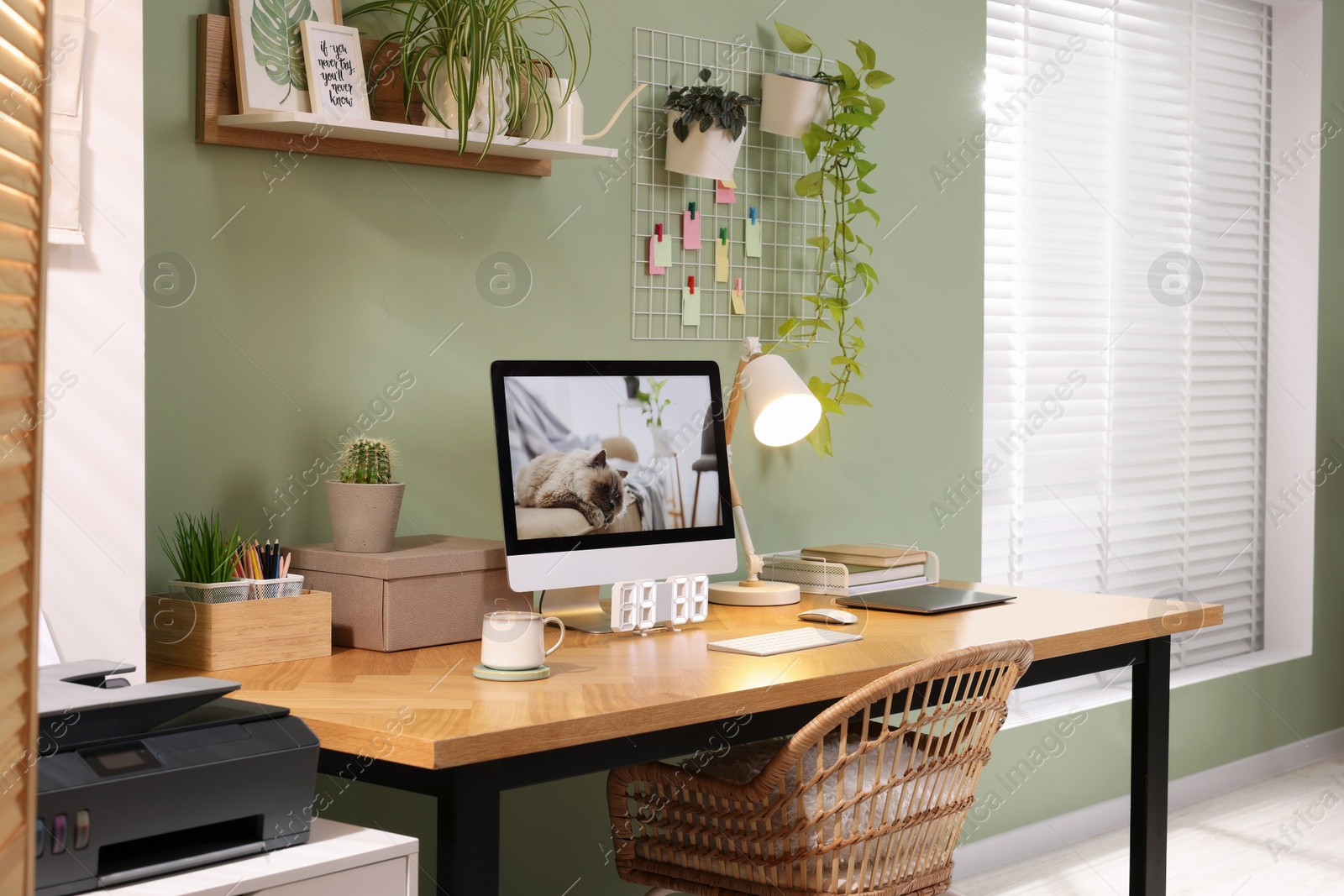 Photo of Stylish workplace with computer, laptop and lamp near olive wall at home