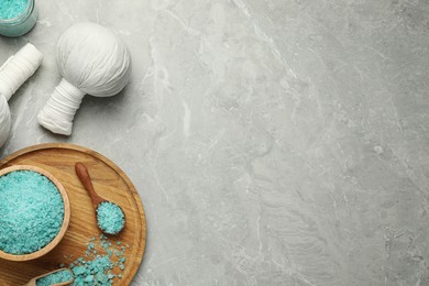 Photo of Spa herbal bags and turquoise sea salt on grey marble table, flat lay. Space for text