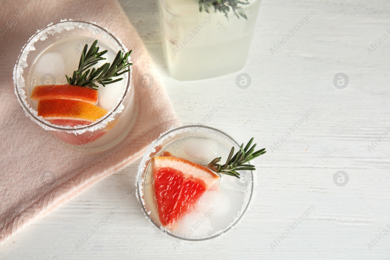 Photo of Glasses of grapefruit cocktails on wooden table, flat lay. Space for text