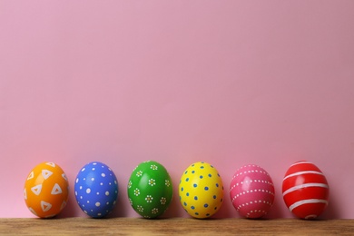 Decorated Easter eggs on table near color wall. Space for text