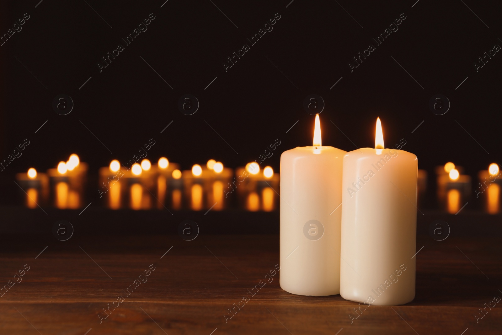 Photo of Wax candles burning on table in darkness