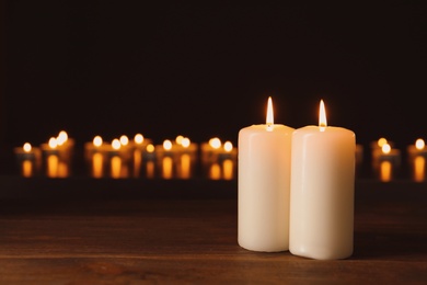 Photo of Wax candles burning on table in darkness