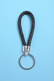 Photo of Black leather keychain on light blue background, top view