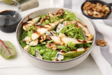 Photo of Delicious pear salad with sauce in bowl on white wooden table, closeup