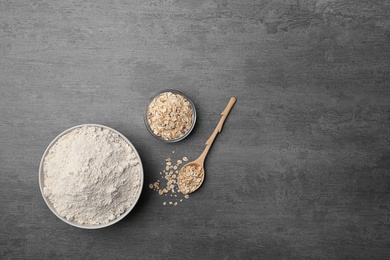 Photo of Bowl with oat flour and flakes in spoon on gray background