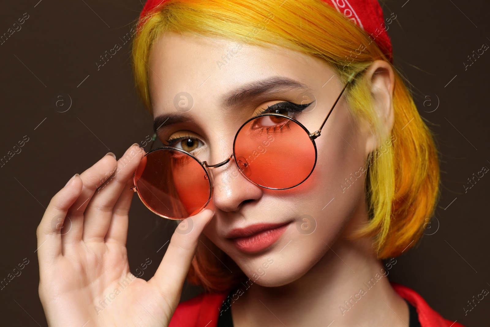 Photo of Beautiful young woman with bright dyed hair on brown background