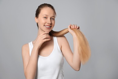Photo of Teenage girl with strong healthy hair on light grey background