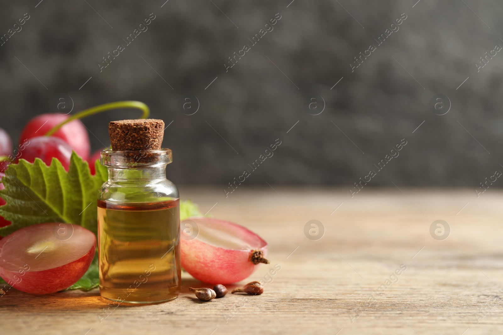 Photo of Bottle of natural grape seed oil on wooden table, space for text. Organic cosmetic