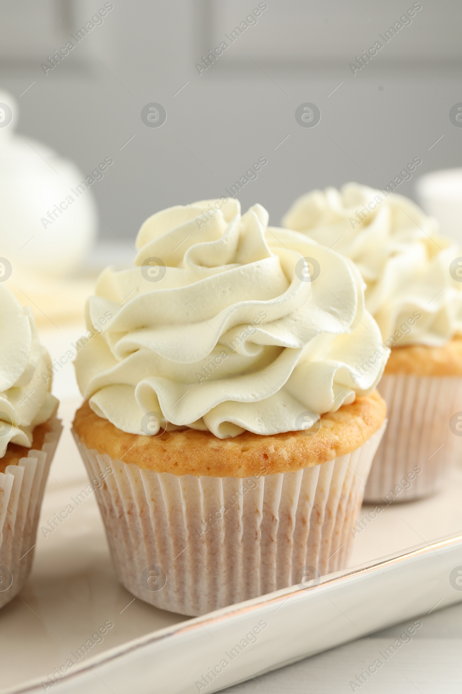 Photo of Tasty cupcakes with vanilla cream on white wooden table, closeup