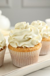 Tasty cupcakes with vanilla cream on white wooden table, closeup