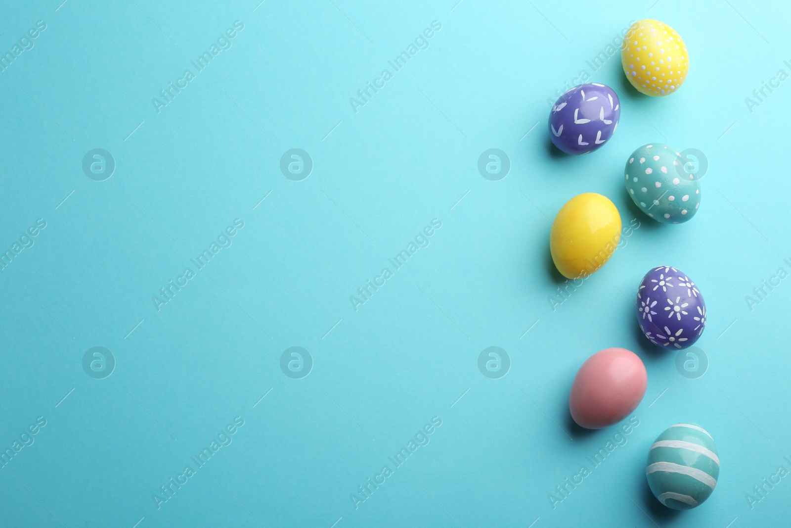 Photo of Flat lay composition of painted Easter eggs on color background, space for text