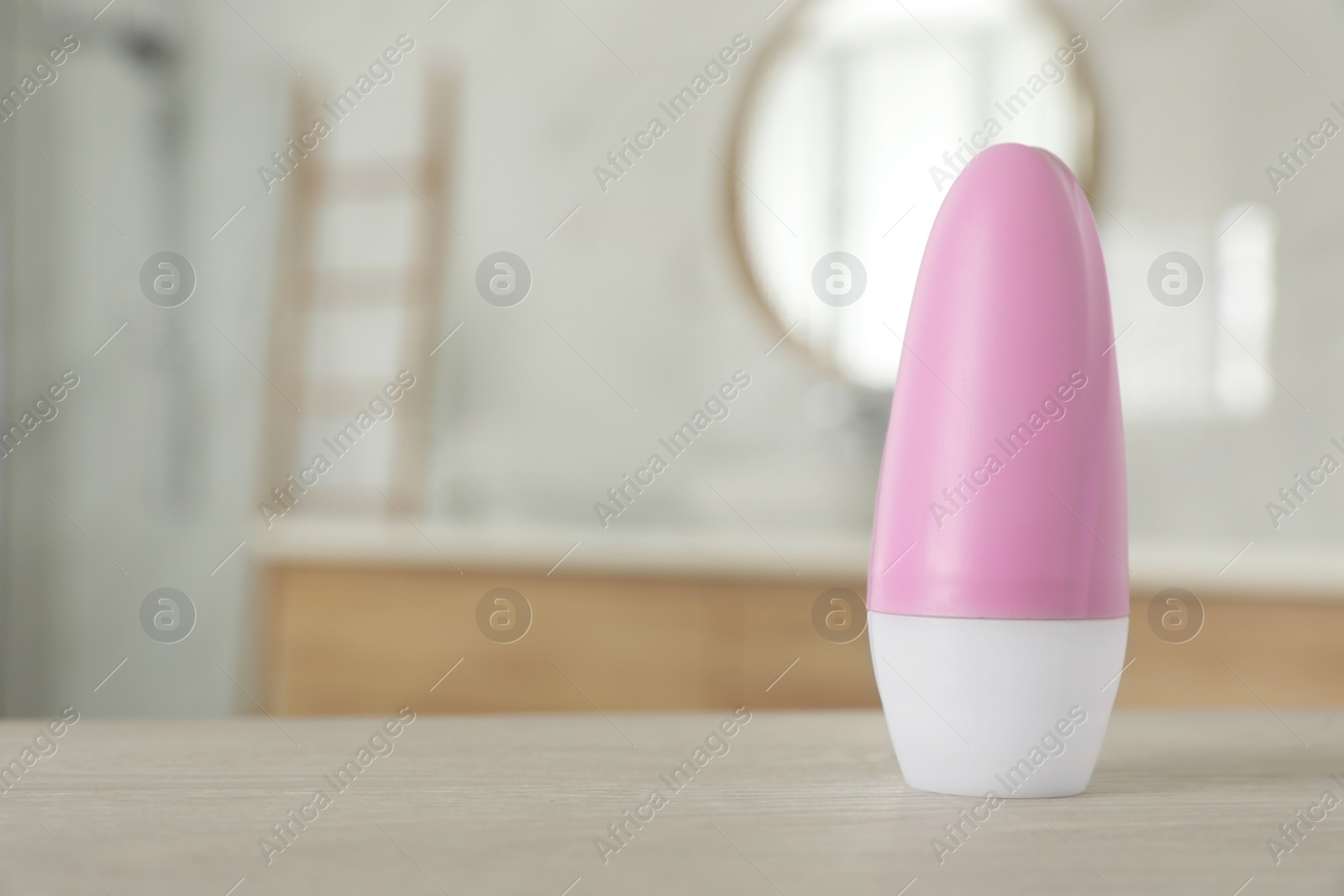 Photo of Female roll-on deodorant on wooden table in bathroom. Space for text