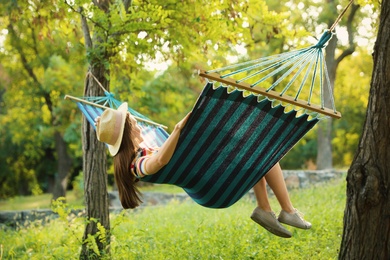 Photo of Young woman resting in comfortable hammock at green garden