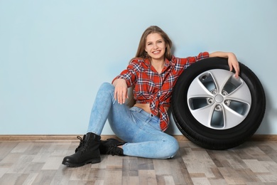 Photo of Young woman in seductive outfit with car tire on grey wall background