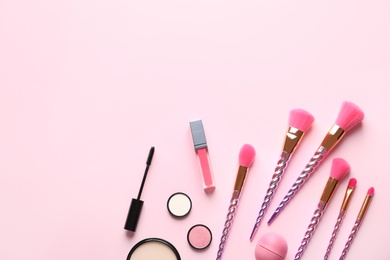Flat lay composition with makeup brushes on pink background. Space for text