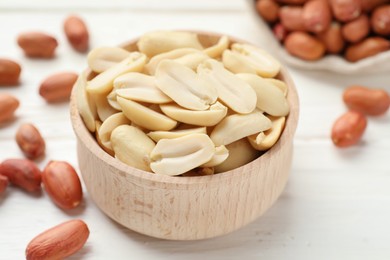 Photo of Fresh peanuts in bowl on white table, closeup