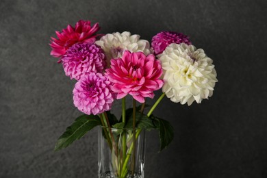 Photo of Bouquet of beautiful Dahlia flowers near dark grey wall, closeup