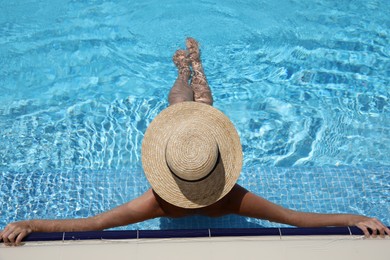 Photo of Woman with straw hat resting in outdoor swimming pool on sunny day, above view