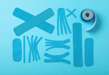 Photo of Different kinesio tape pieces and roll on light blue background, flat lay