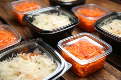 Plastic containers with tasty vegetable salads on wooden table, closeup. Food delivery service