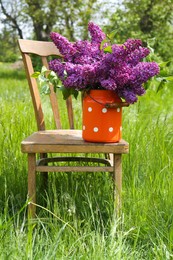 Photo of Beautiful lilac flowers in milk can outdoors