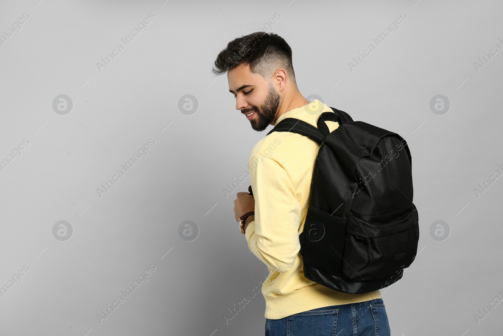 Photo of Young man with stylish backpack on light grey background. Space for text