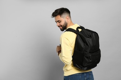 Young man with stylish backpack on light grey background. Space for text