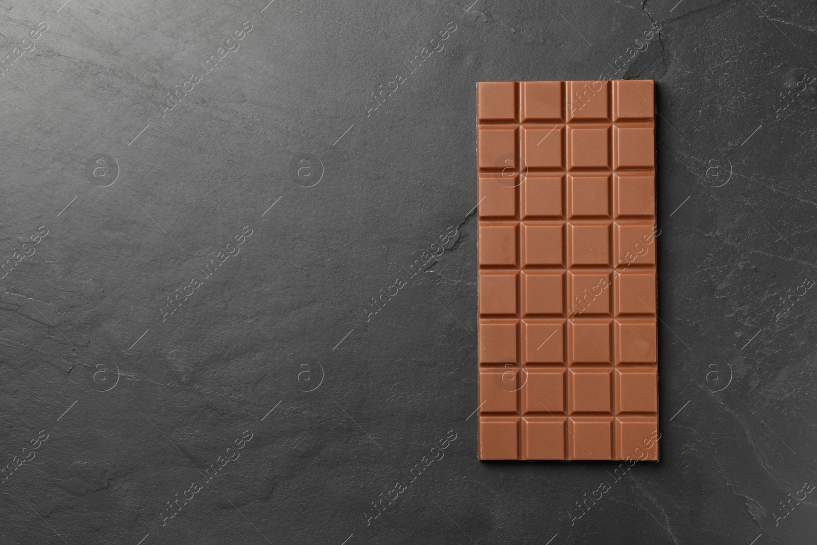 Photo of Tasty chocolate bar on grey table, top view. Space for text