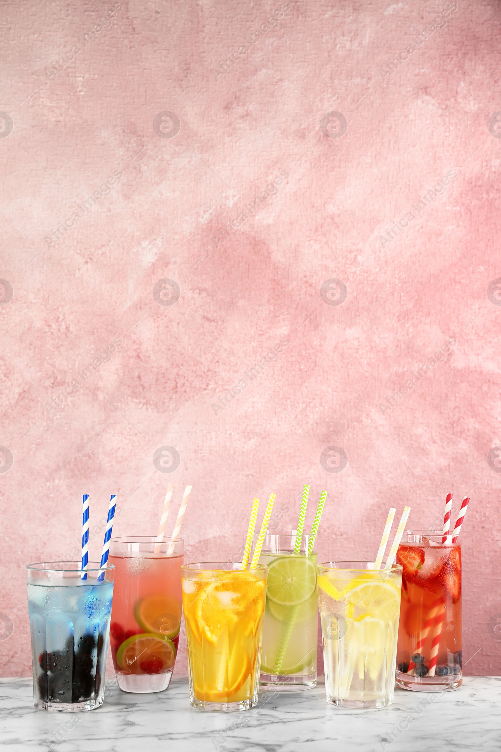 Photo of Glasses with lemonades on table against color background