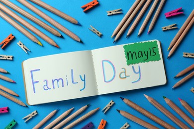 Photo of Happy International Family Day. Flat lay composition with notebook and stationery on light blue background