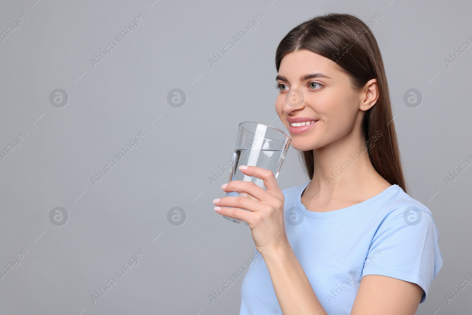 Photo of Healthy habit. Woman holding glass with fresh water on grey background. Space for text
