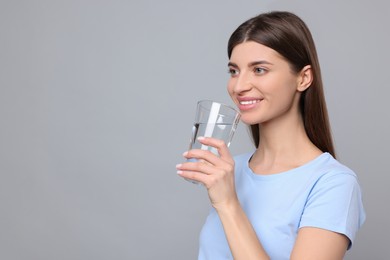 Healthy habit. Woman holding glass with fresh water on grey background. Space for text