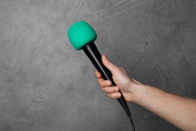 Woman holding microphone on color background