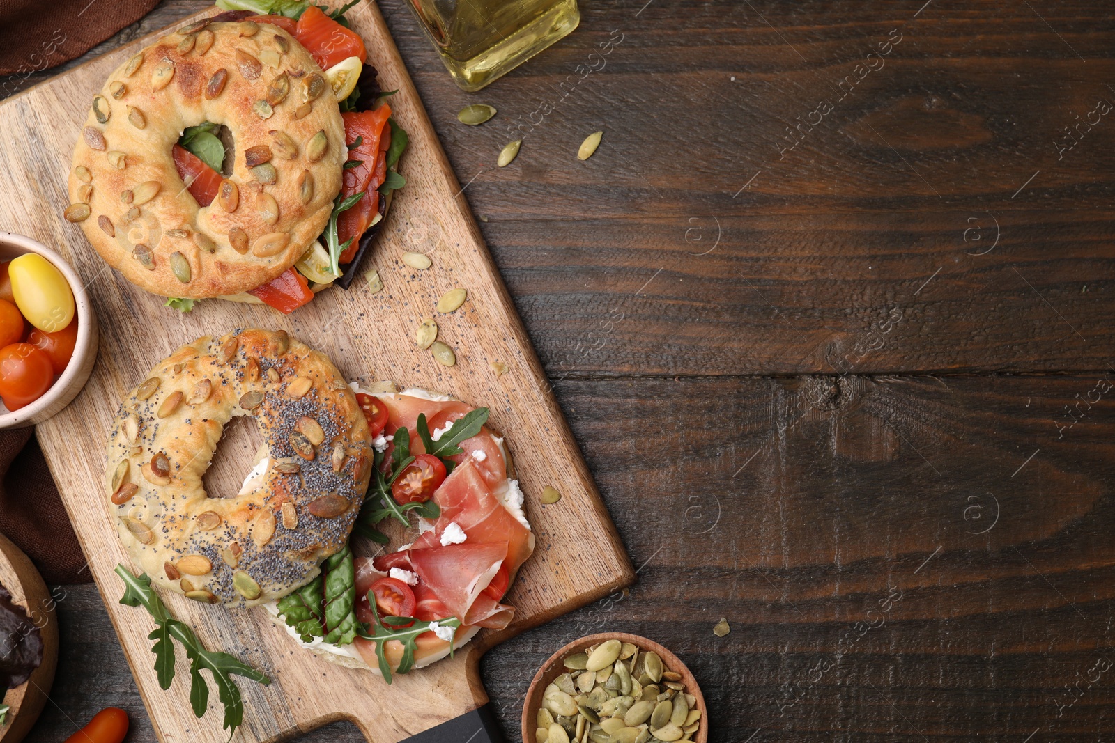 Photo of Tasty bagel sandwiches on wooden table, flat lay. Space for text