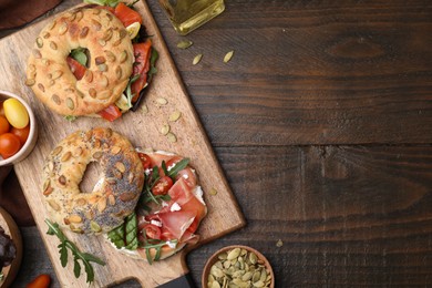 Photo of Tasty bagel sandwiches on wooden table, flat lay. Space for text